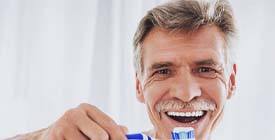 Smiling man with dental implants in Roselle Park holding a toothbrush