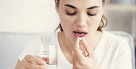 woman taking a pill with a glass of water 