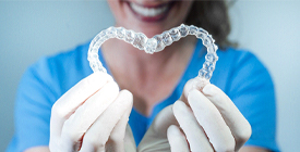 An up-close look at a dental professional holding two Invisalign aligners and forming the shape of a heart