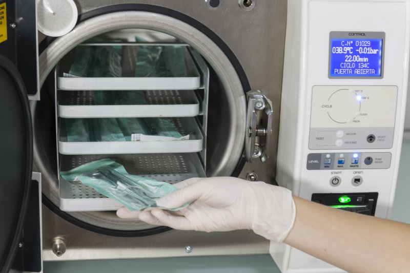 a dental staff member using an autoclave to sanitize dental instruments