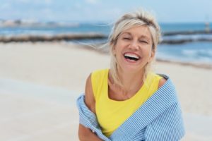 woman smiling with implants at the beach 