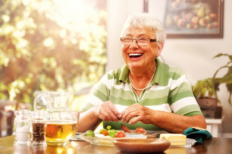 Woman with dental implants smiling at dinner table