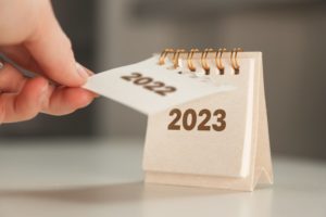 a person removing a piece of paper that says "2022" to reveal a piece of paper that says "2023" beneath it