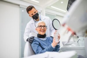 Senior dental patient admiring her smile in the mirror